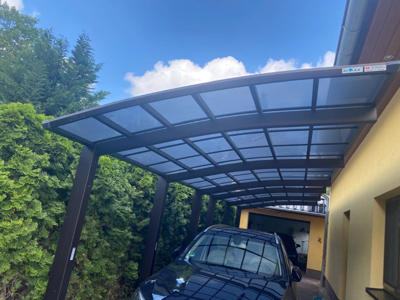 Aluminium-Carport mit geschwungenem Dach neben einem Wohnhaus in Brandenburg