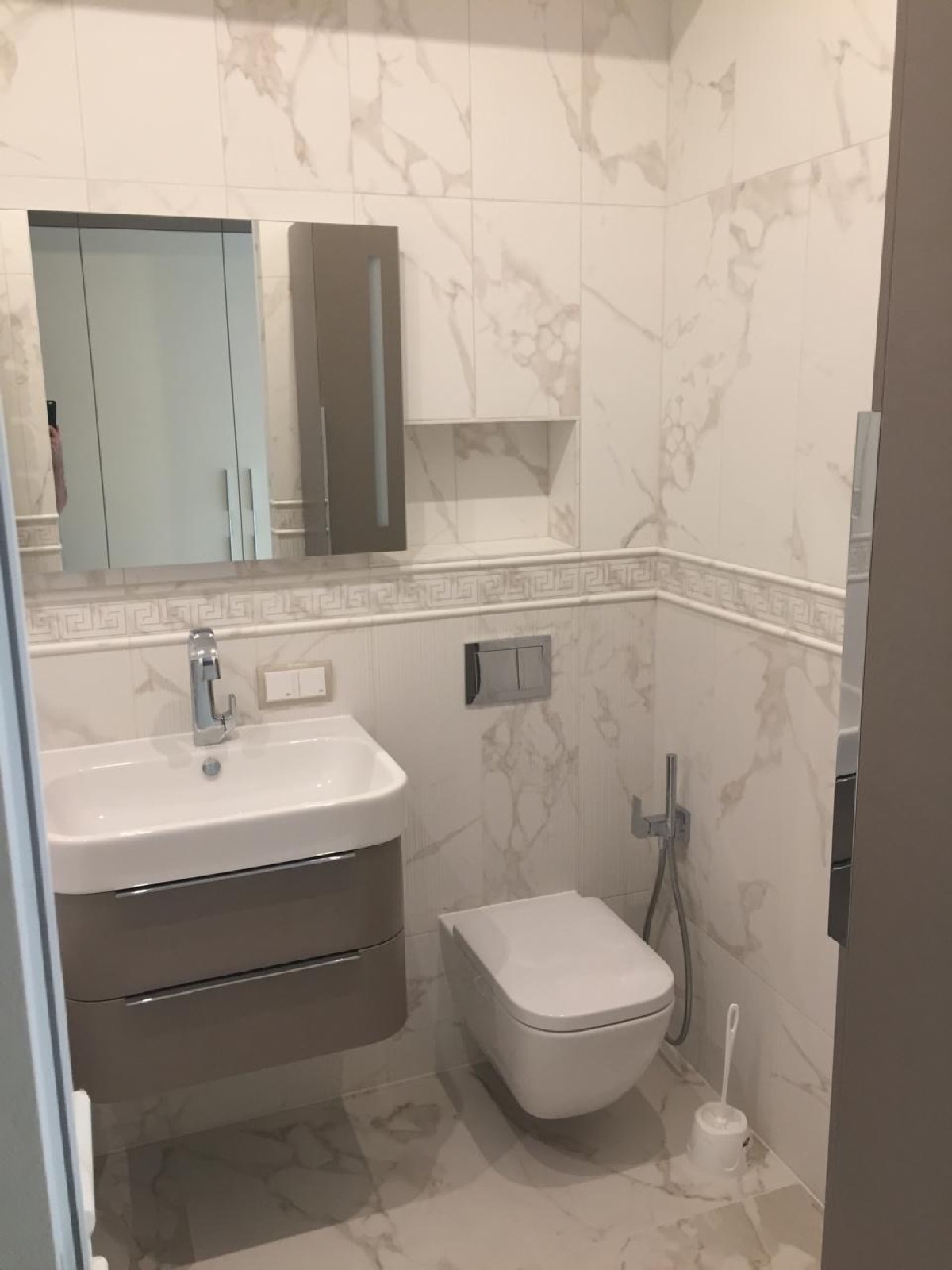 Modernes Badezimmer mit Marmoroptik-Fliesen, Waschtisch und Spiegelschrank