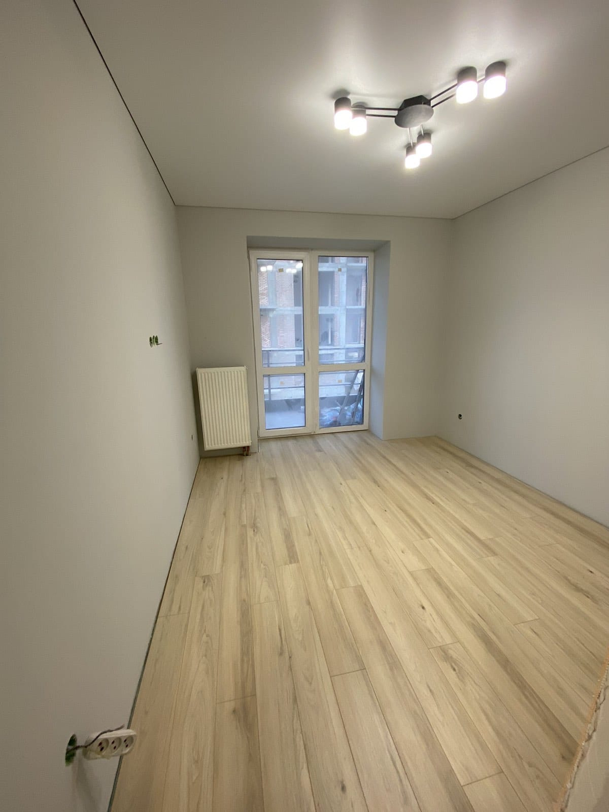 Innenraum im Ausbau: glatte, helle Wände, neu verlegter heller Boden, Elektroinstallation noch offen